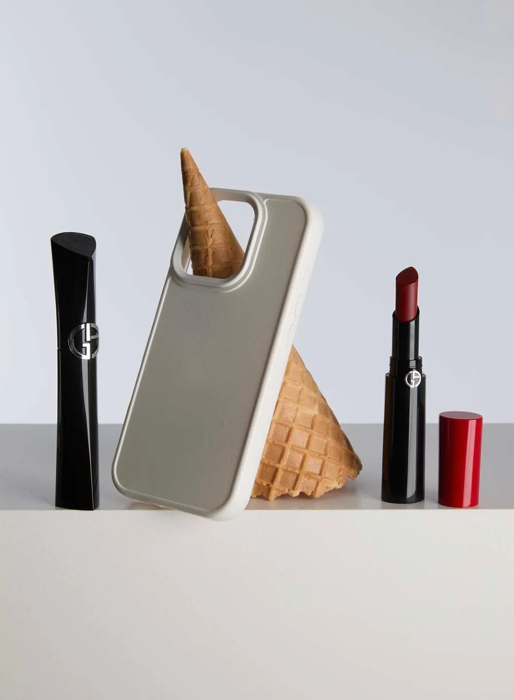 Mascara und Lippenstift von Armani Beauty neben einem Smartphone und einer Eistüte (shotview.com)