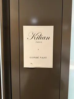 Ein Schild mit der Aufschrift Kilian Paris × Condé Nast an der Tür zum Set