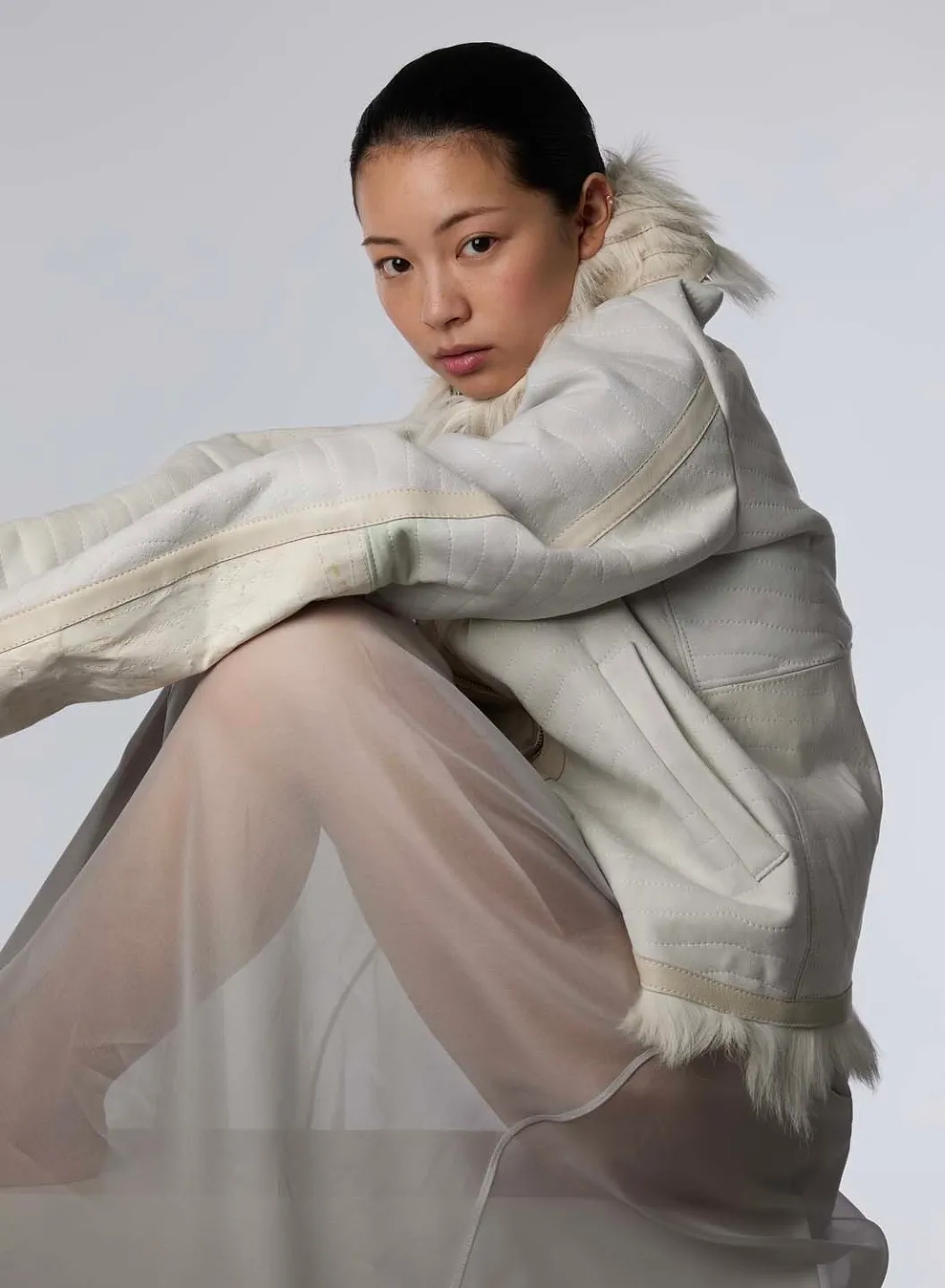 TingTing Lai sitzend in einer cremefarbenen Jacke und transparenter Hose (shotview.com)