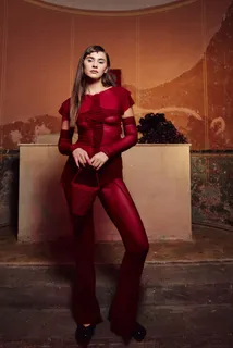Guest in a red outfit against a warmly lit wall