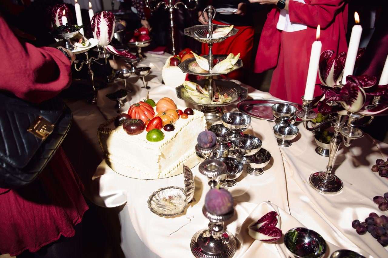 Guests in red around a long table with candles, cake, fruit and radicchio at The Female Company launch event