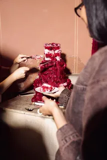 Guests cutting into a red cake