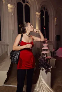 Guest in a red dress with a glass next to the chocolate fountain