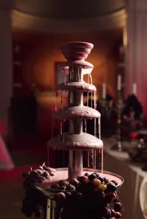 Chocolate fountain with grapes under red light