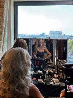 Aliona Gris bei Hair und Make-up vor einem Spiegel, hinter dem Fenster die Stadt