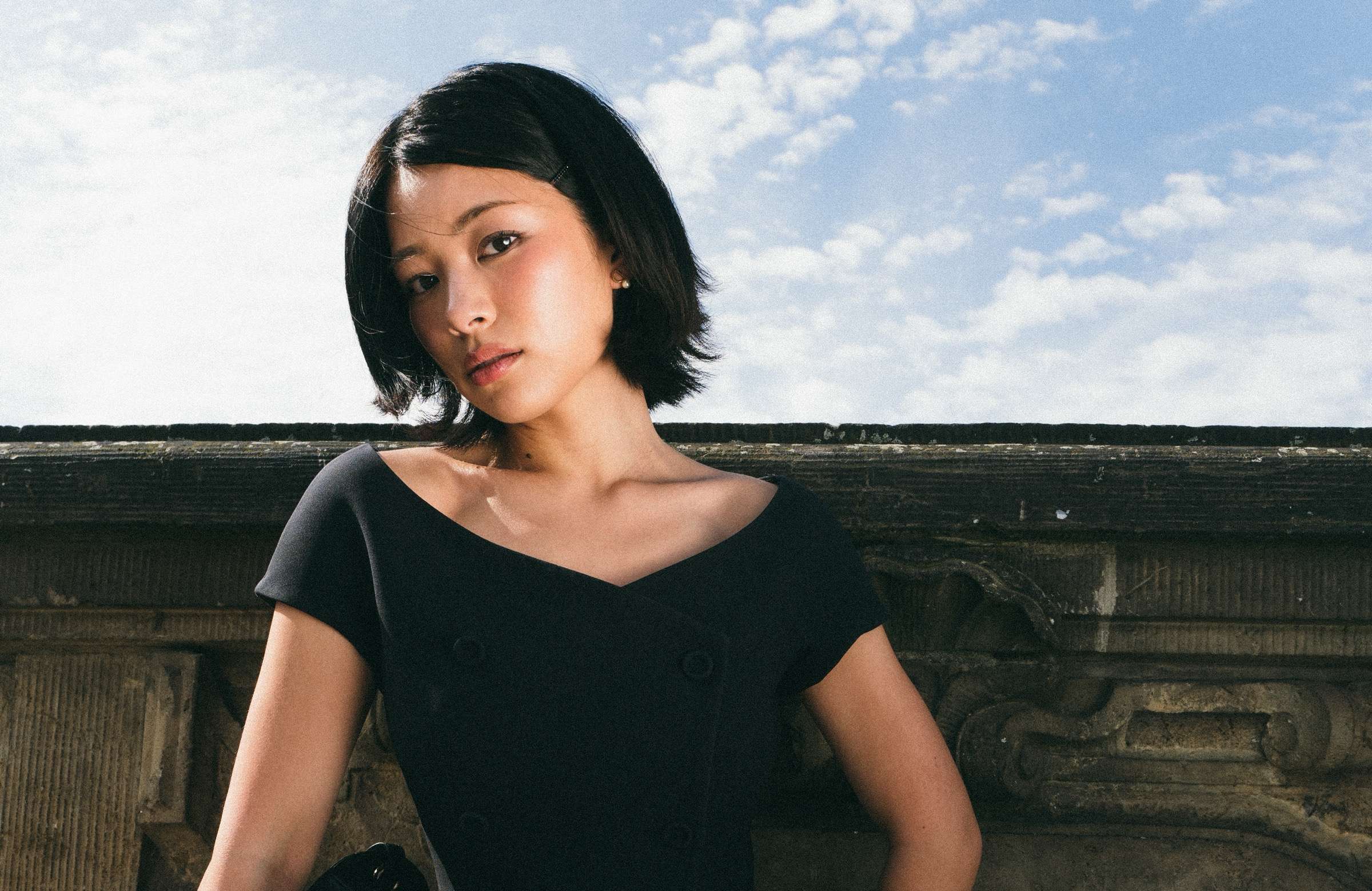 TingTing Lai in a black Dior top against a stone balustrade under a blue sky, Berlin