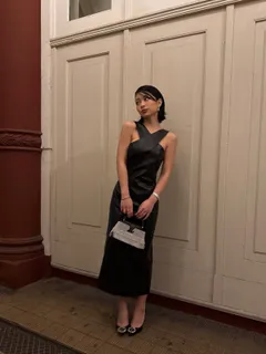 TingTing Lai in schwarzem Kleid mit Louis-Vuitton-Tasche in einem Hotelflur