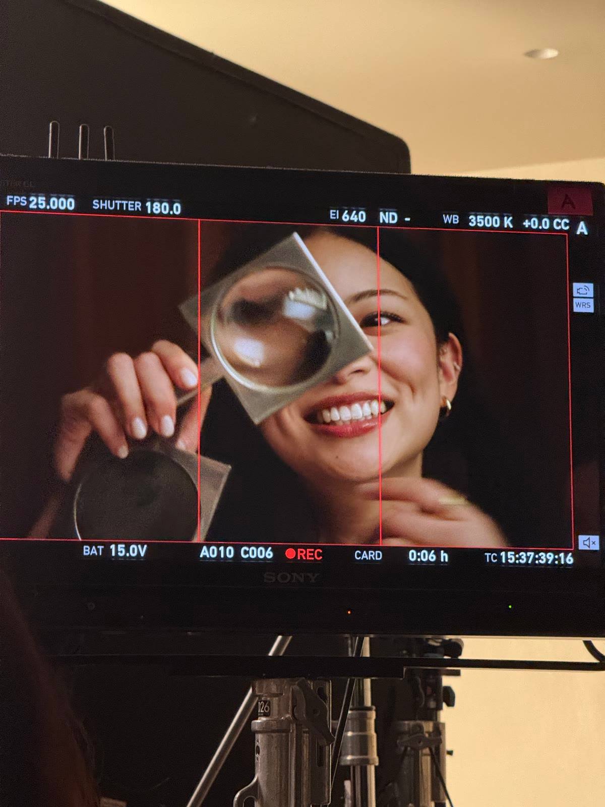 A monitor showing TingTing Lai laughing behind a magnifying glass