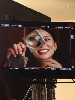 Ein Monitor zeigt TingTing Lai lachend hinter einer Lupe