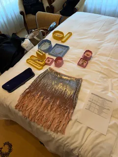 Requisiten auf einem Bett: ein Paillettenrock, Schmuck und ein Skript