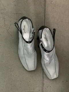 Ein Paar silberne Schuhe mit Knöchelriemen auf dem Studioboden